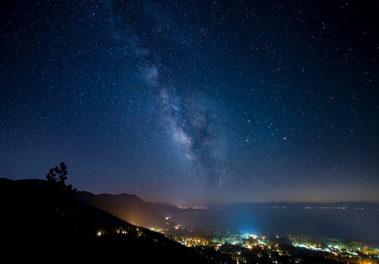 Captivating view of the Milky Way galaxy over the serene Lake Tahoe with twinkling city lights.